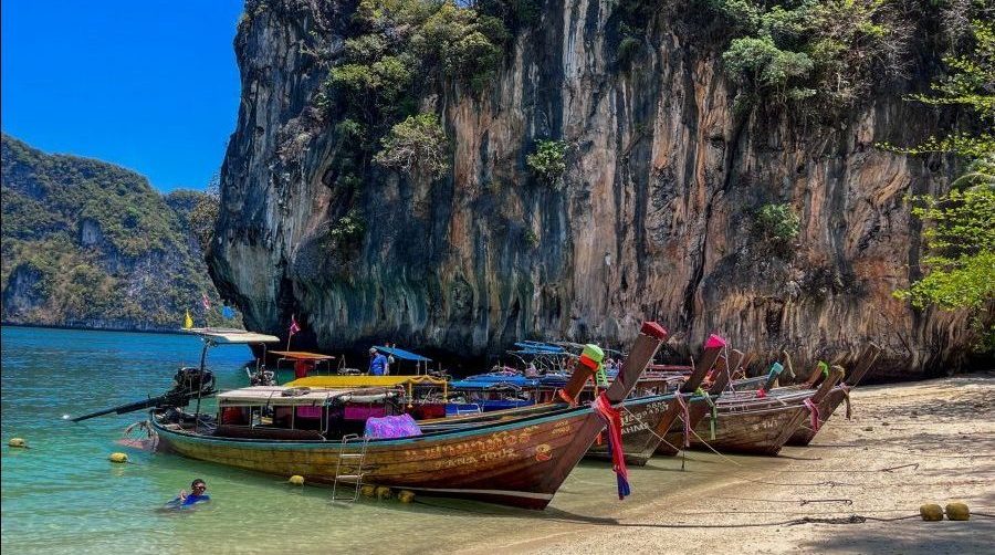 Traditional long-tail boats lined up on a picturesque Thai beach, ready for adventure on our 2-week Thailand itinerary.