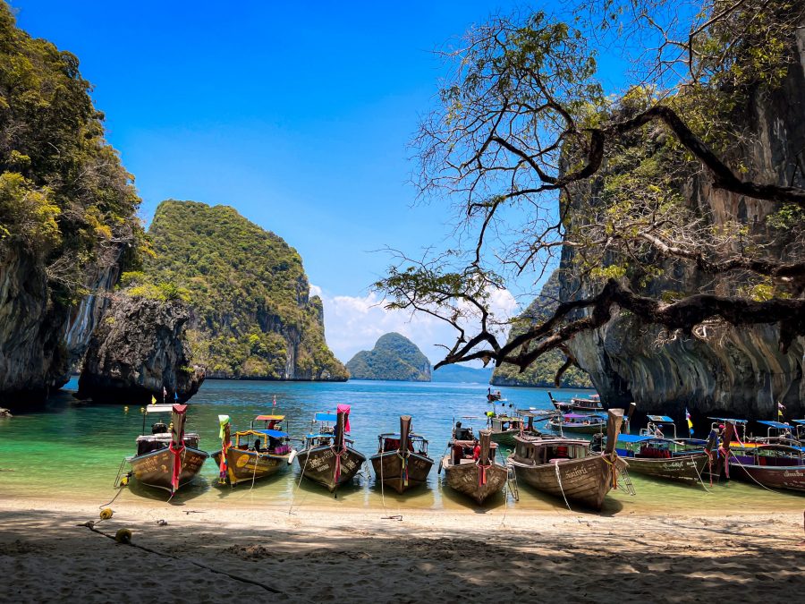 Thailand's Four Island Tour - Traditional Thai longtail boats moored by the sandy shores of a tropical island, surrounded by turquoise waters