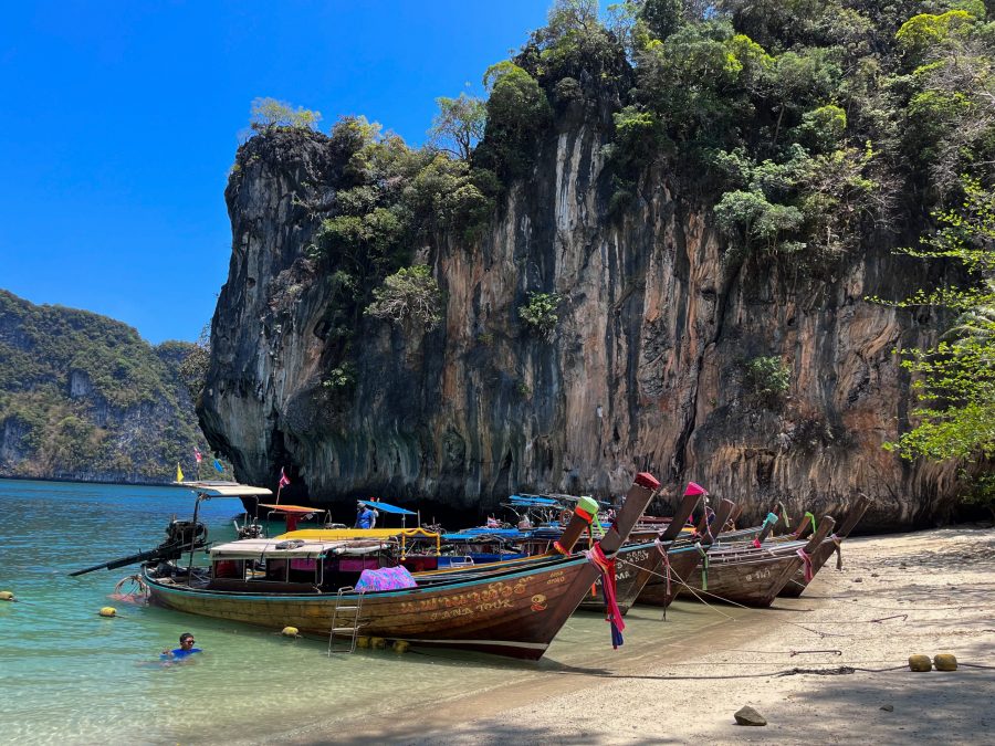 Longtail boats on the beach with limestone cliffs in the background