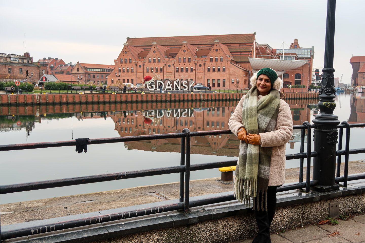 By the waterfront with Gdańsk sign in the back with a santa hat