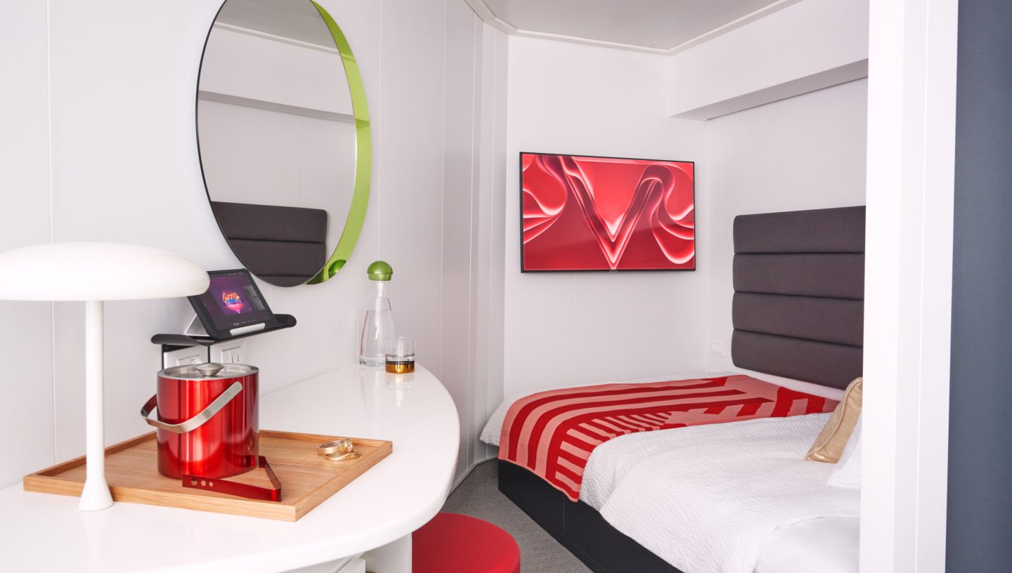 Interior of a Virgin Voyages Scarlet Lady cruise cabin showing bed, storage, and modern design
