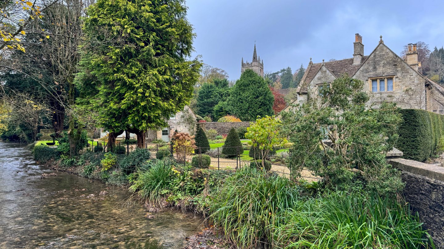 A quiet Cotswolds village lined with traditional honey-coloured stone houses, flower gardens and a river.