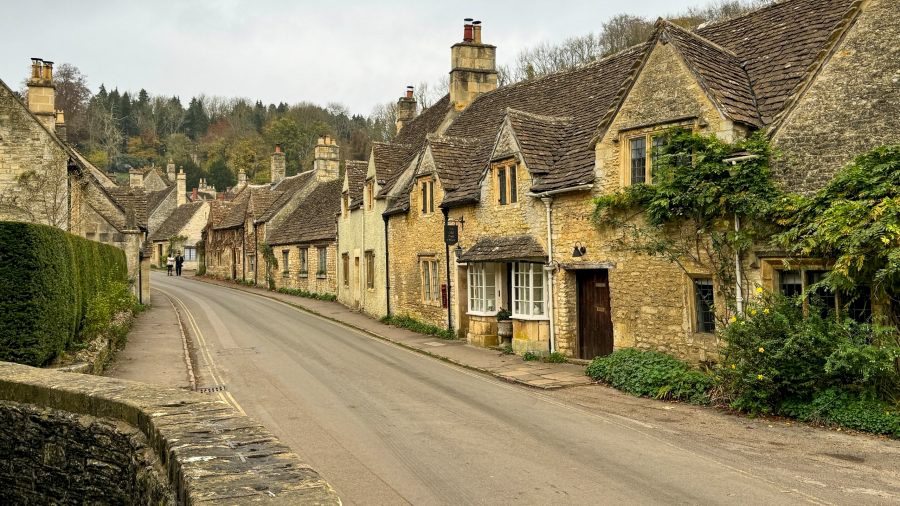 The iconic honey-coloured stone cottages of Castle Combe village, known as the prettiest village in the Cotswolds.
