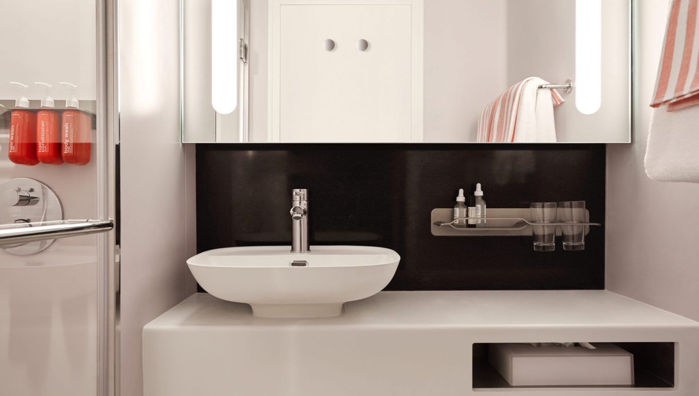 Modern bathroom inside a Virgin Voyages cruise cabin, showing compact layout and storage