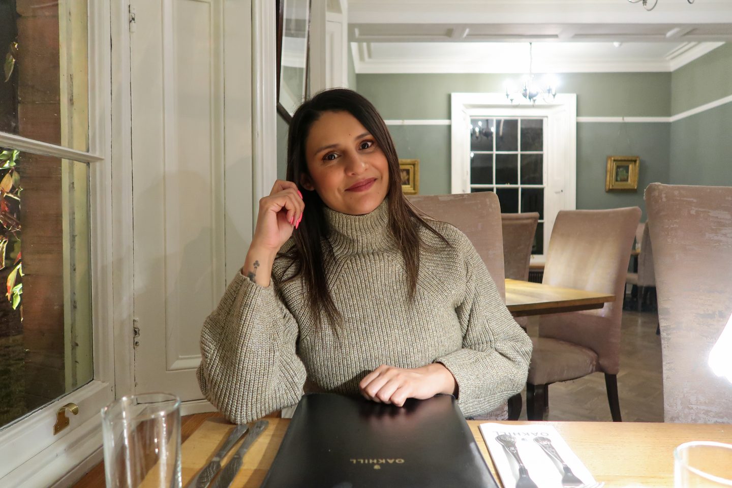 A woman sitting at the table with a menu at Oakhill Cromford during a Peak District walking and wellness break.