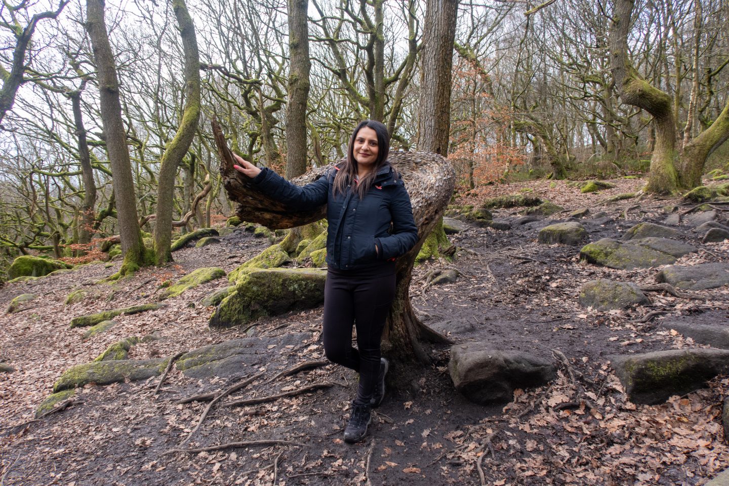 A woman standing by the Money Tree (or Penny Tree) on the Padley Gorge trail during a Peak District walking and wellness break.