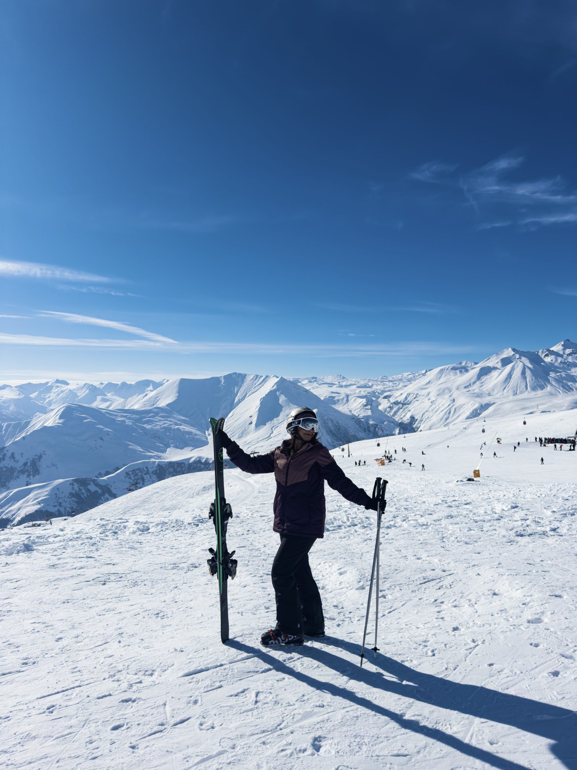 Woman standing in snow in the mountains of Gudauri with skis and poles ready for her first time skiing in Gudauri