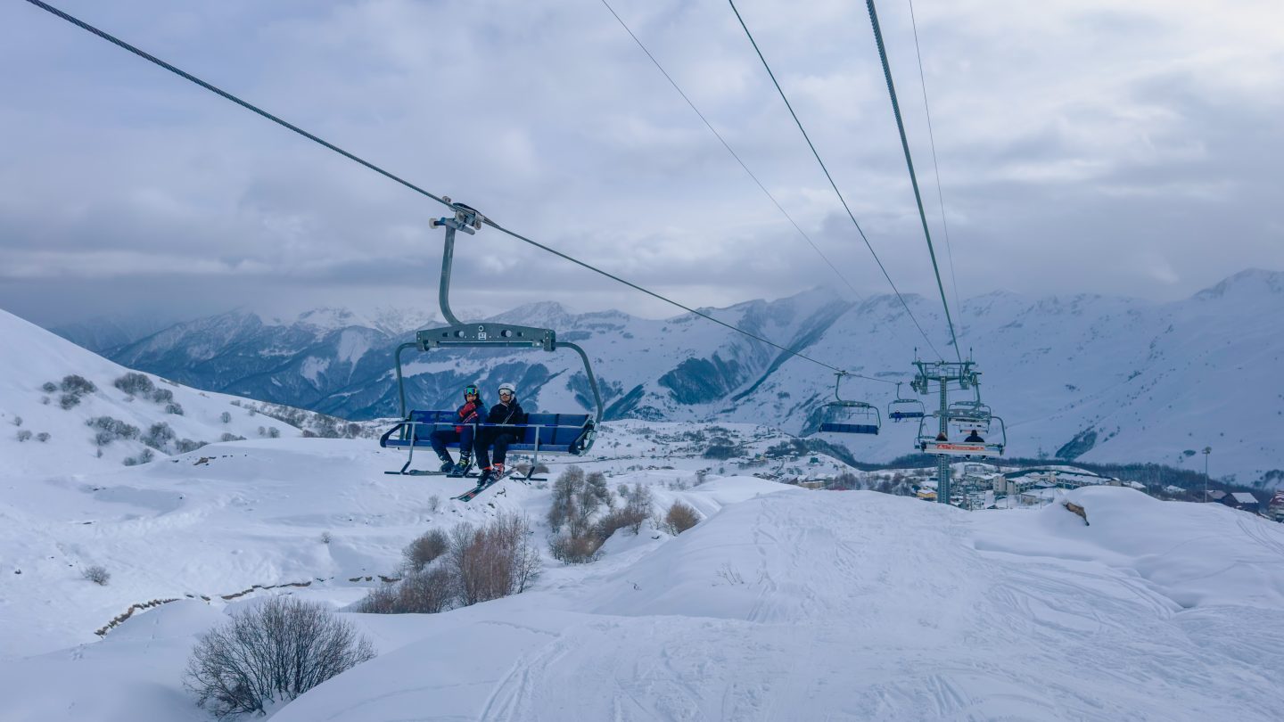 Chair lifts with snow all around and mountains in the background