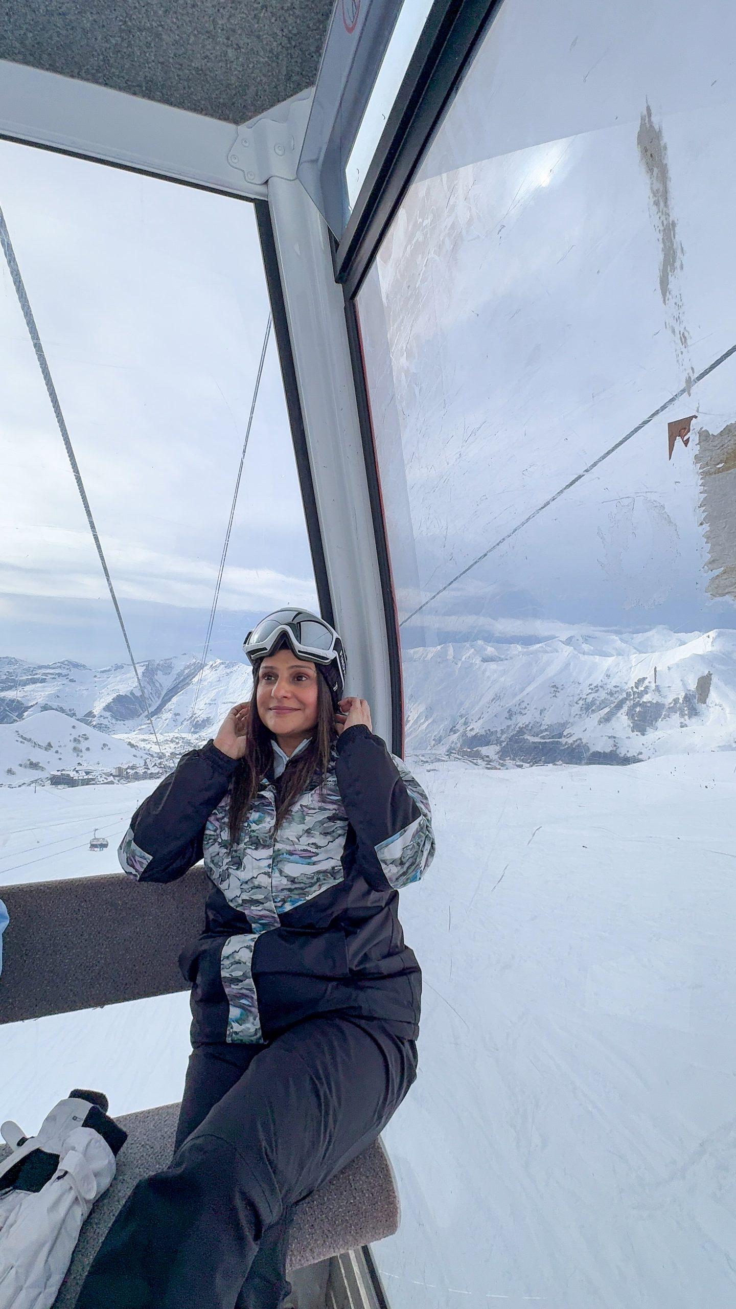 Woman sitting in a gondola with snow-filled mountains in the background