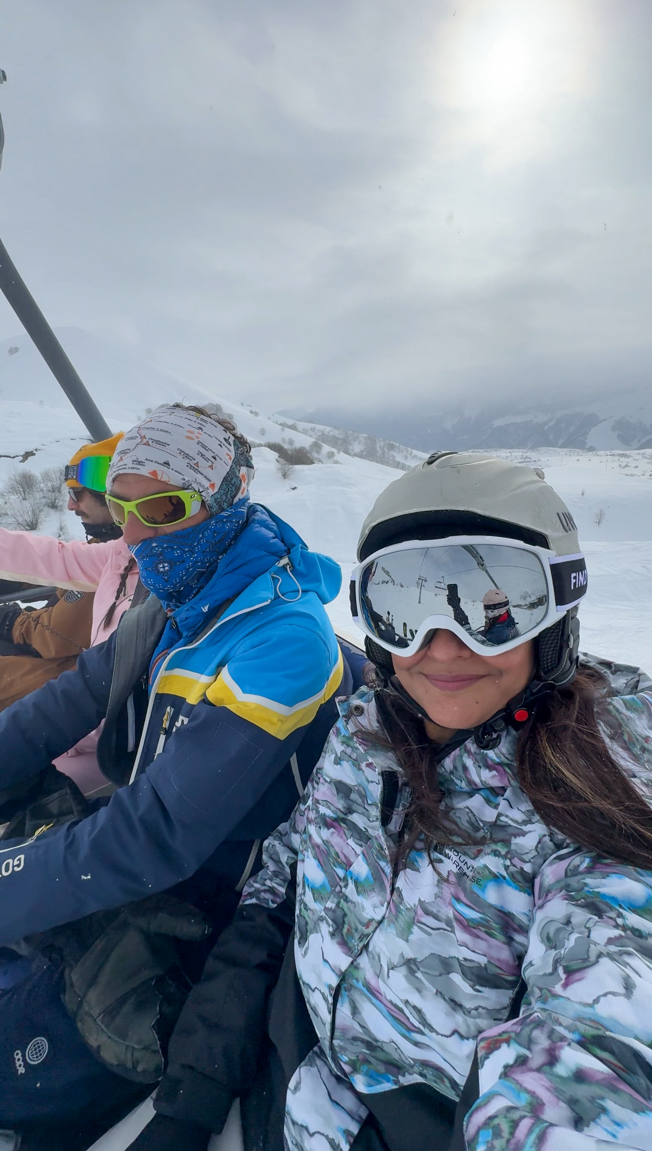 Girl on chair lift wearing goggles and a helmet