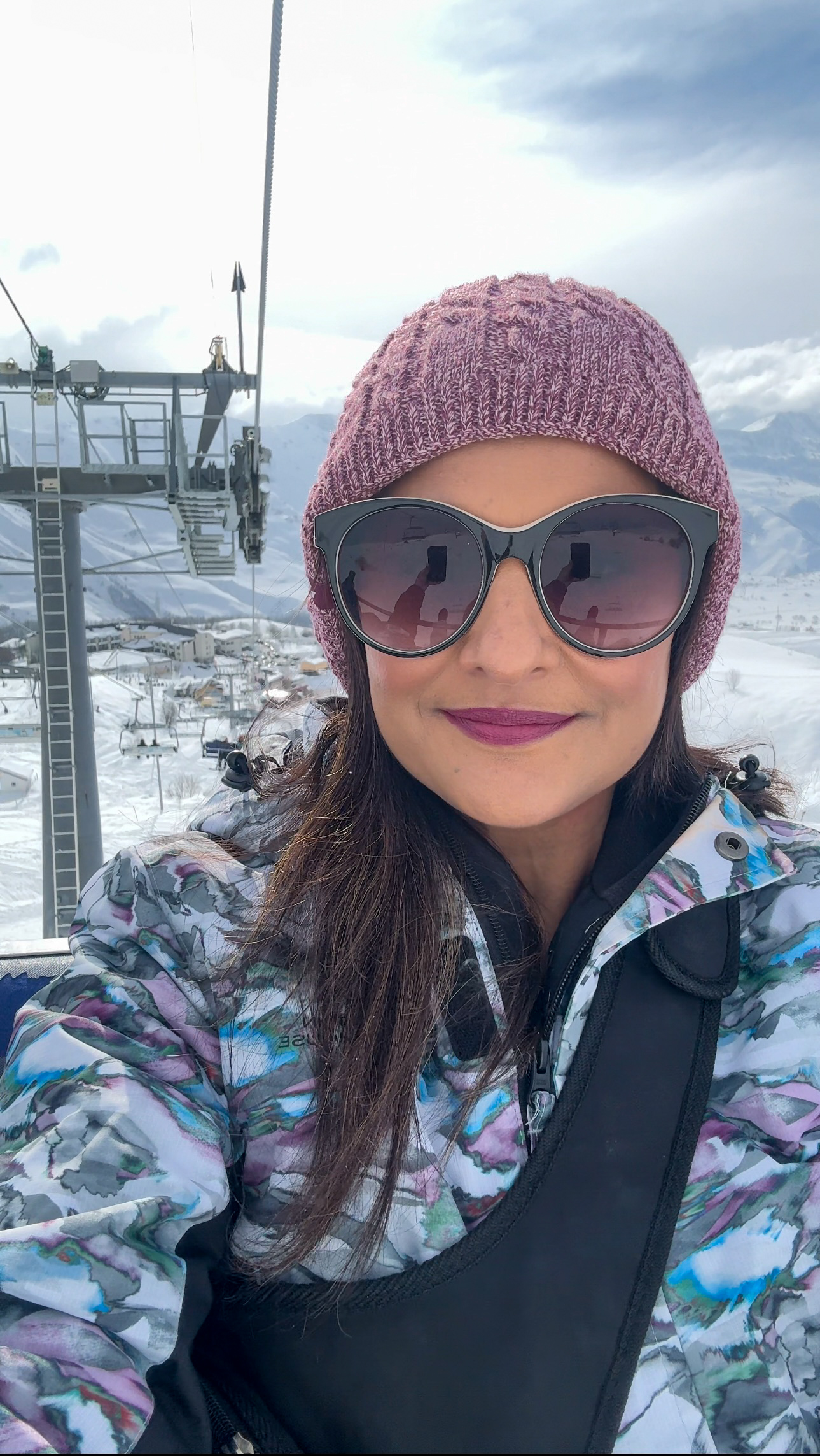 Girl on a chair lift wearing hat and sunglasses