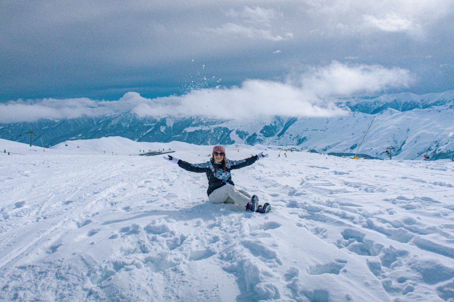 Woman sitting in snow in the mountains of Gudauri