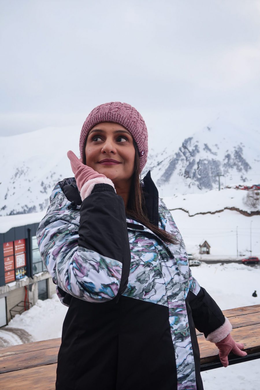 Woman dressed in hat, gloves and ski jacket with the mountains of Gudauri in the background