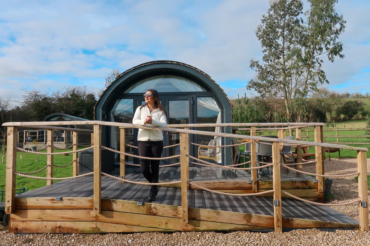 A woman stands outside a luxury glamping pod at 3Trees in Matlock, during a Peak District walking and wellness break.