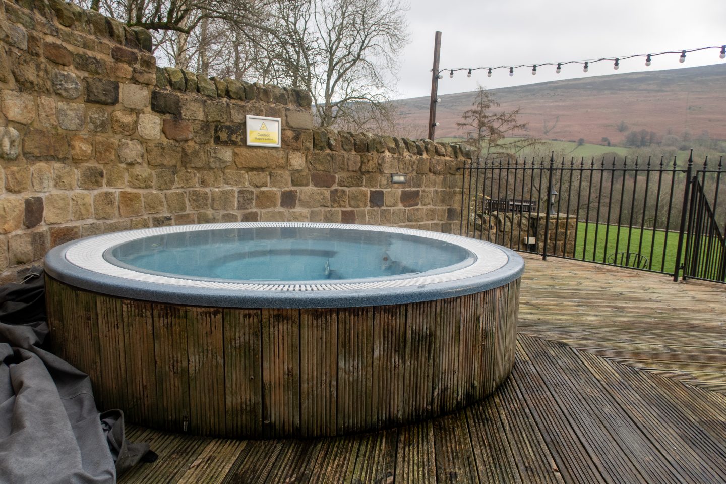 A hot tub on a decking area facing rolling hills at Losehill Hotel and Spa