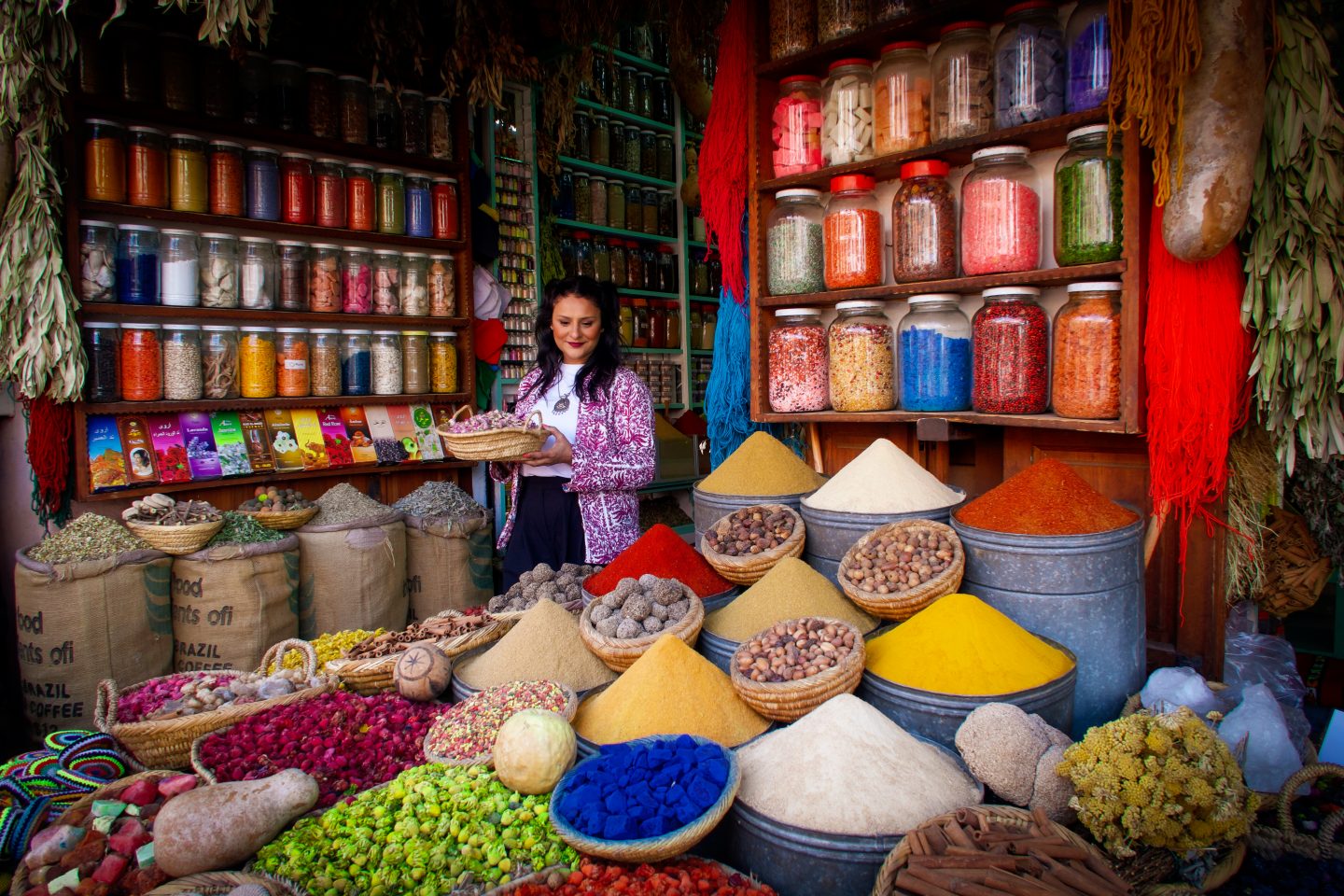 Woman holding a basket of spices at a stall of colourful spices
