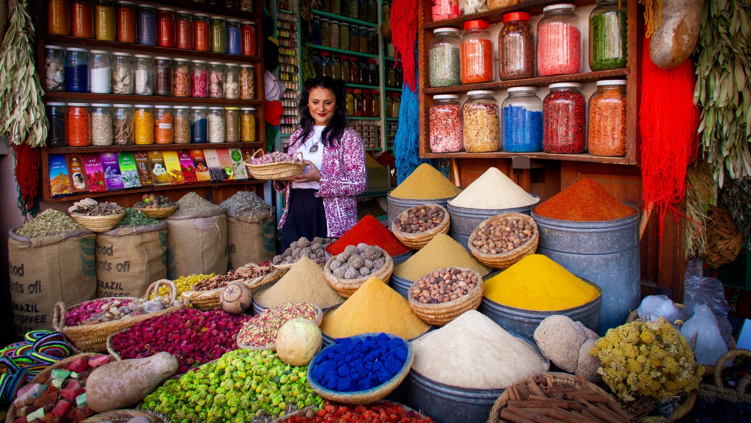 Woman holding a basket of spices at a stall of colourful spices