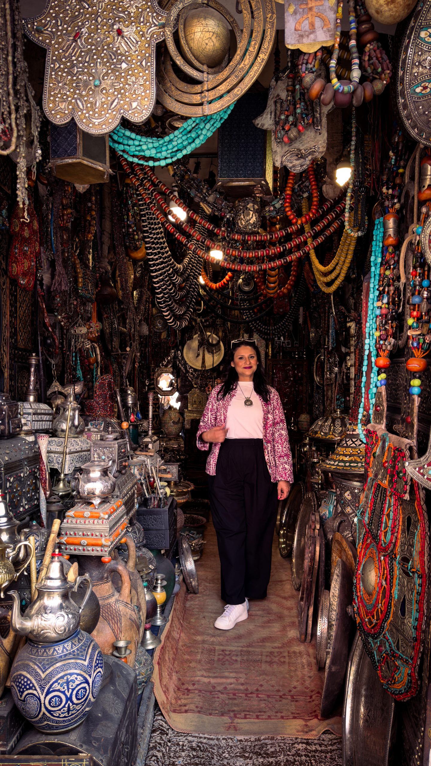 Woman standing in a souk shop with lamps, jewellery and decorations hanging above