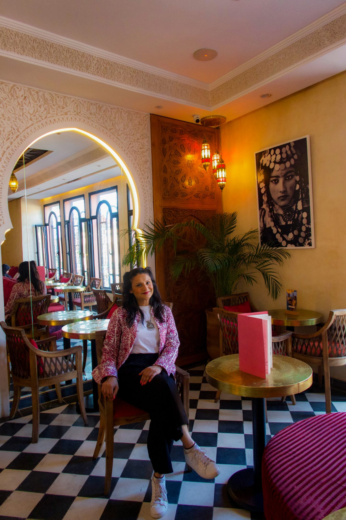 Woman sitting in a cafe with pink decor