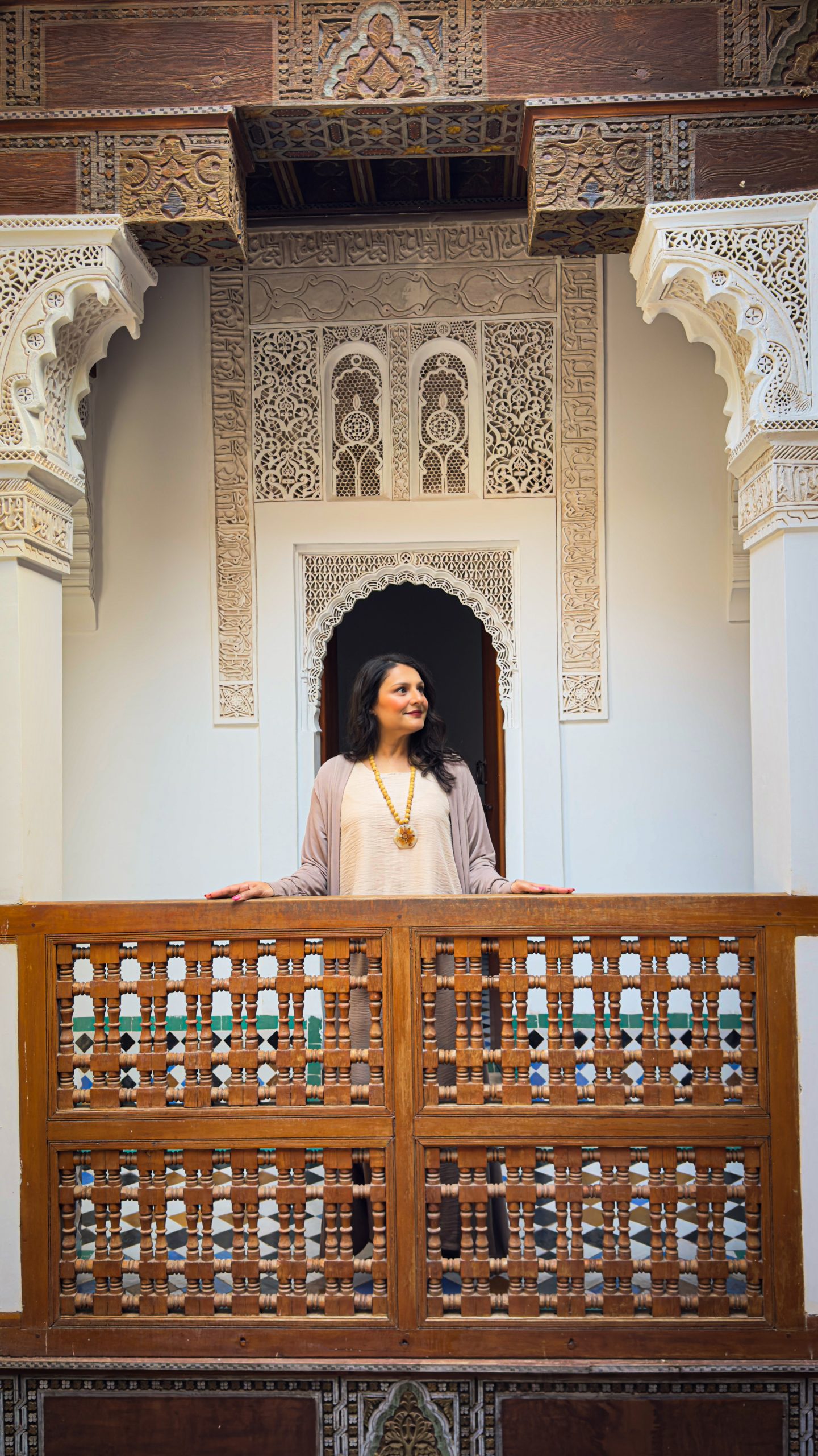 Woman standing on a wooden balcony at Ben Youssef Madrassa