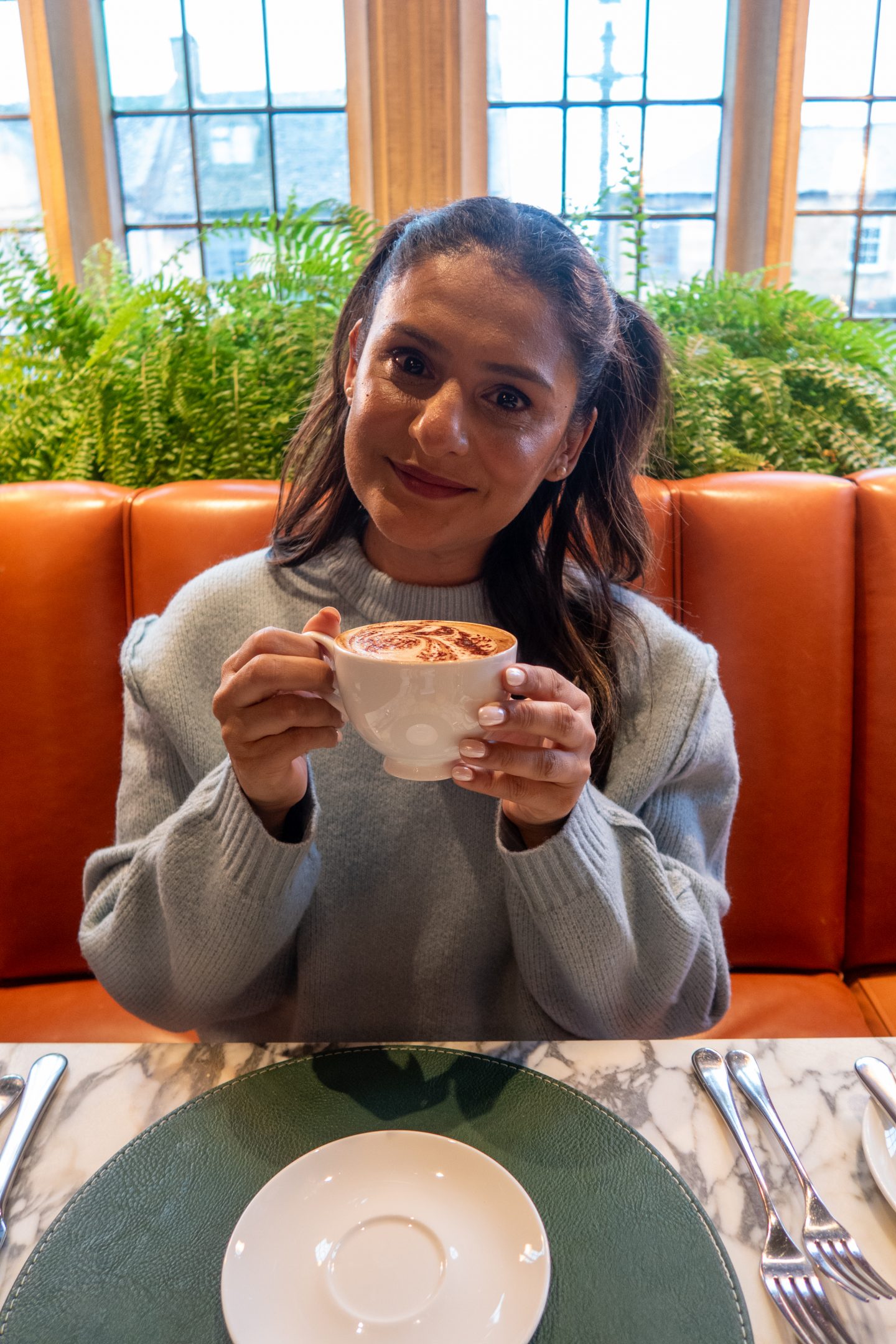 Woman smiling holding a cup of tea in her hands at The Lygon Arms