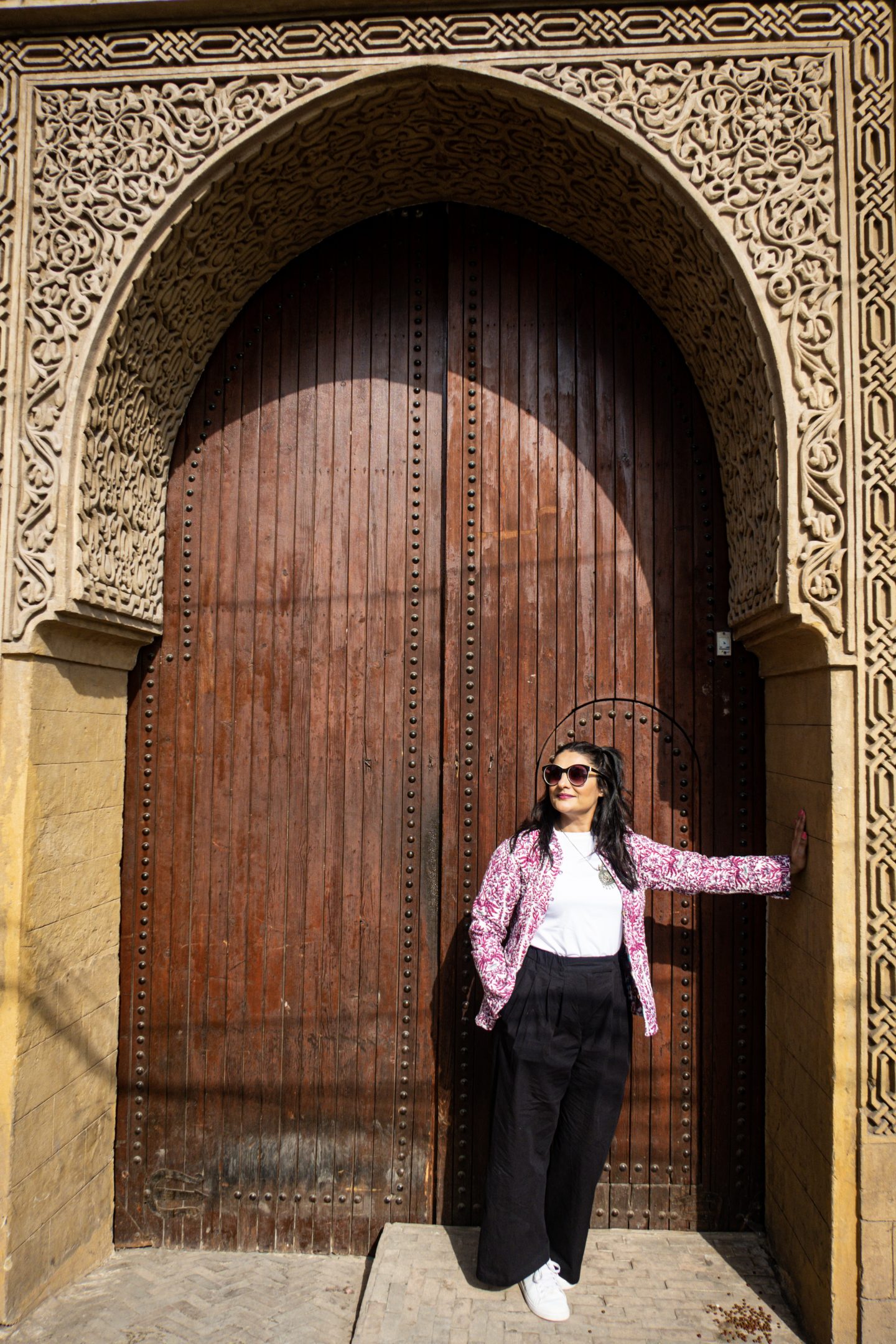 Woman standing in a doorway with big wooden doors and intricate carvings