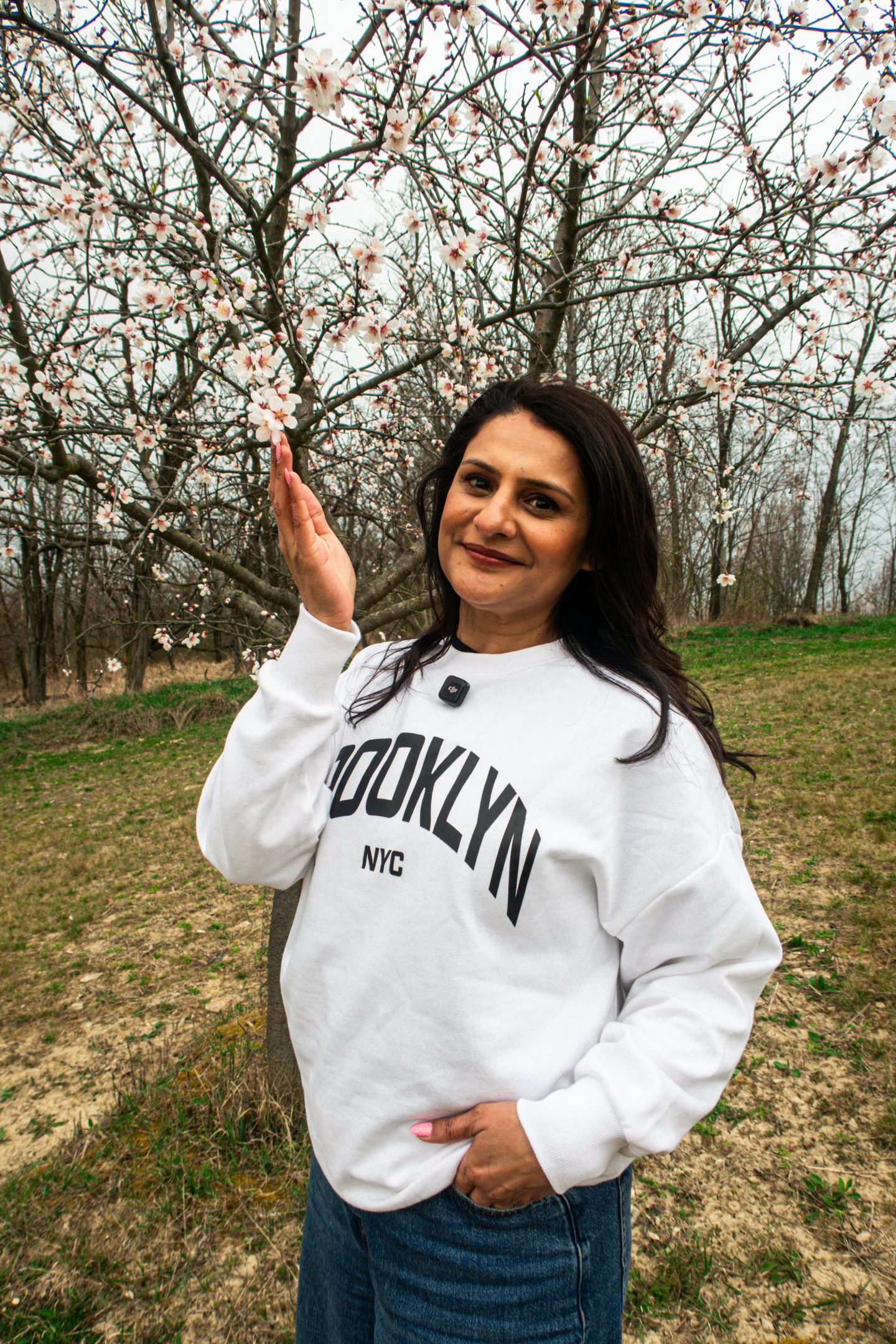 A woman standing in an Almond Orchard during the Blossom Festival