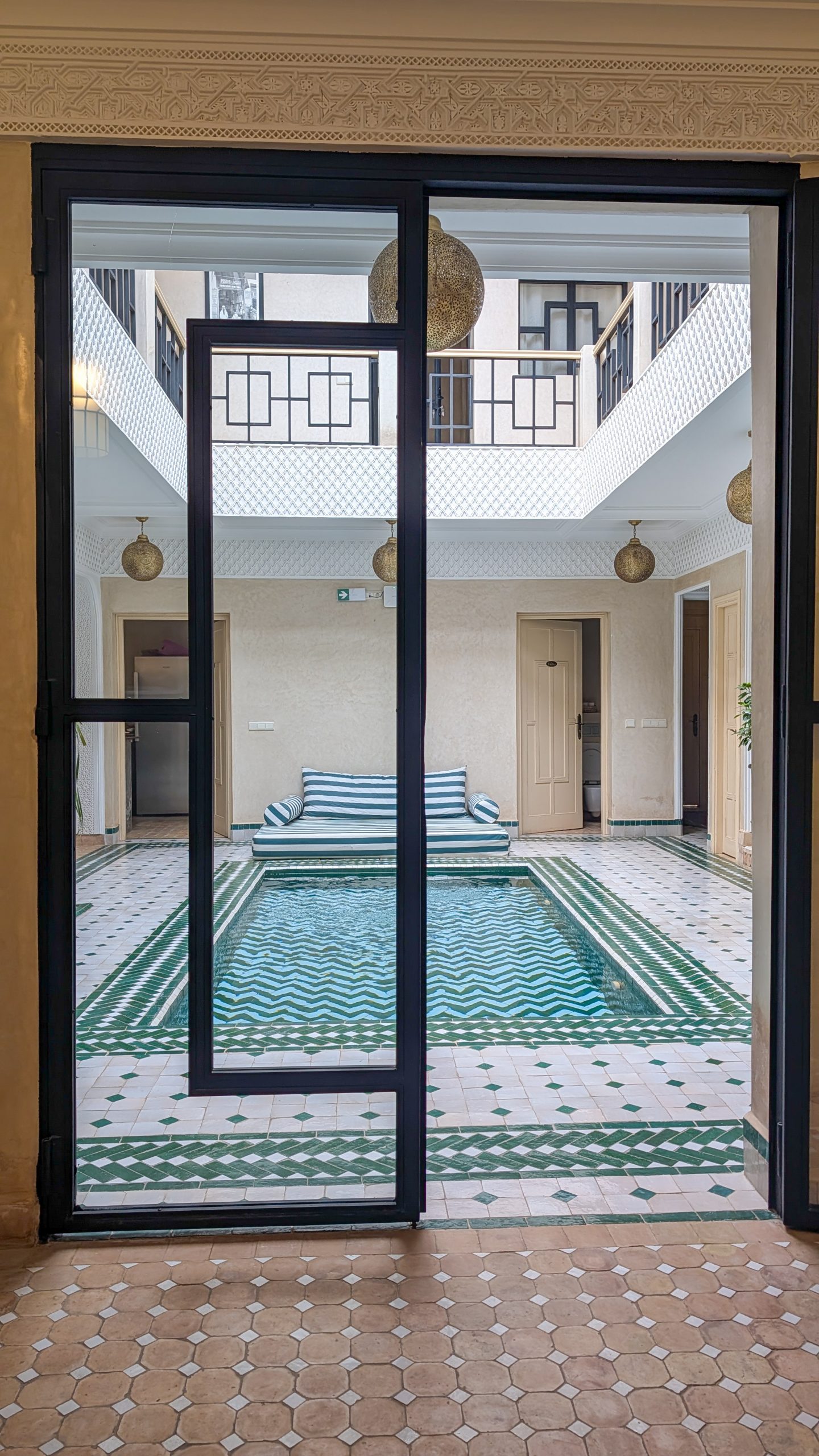 View from behind glass doors of a pool in a Riad